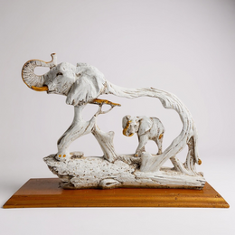 Decorative sculpture of two elephants on a wooden base against a plain background